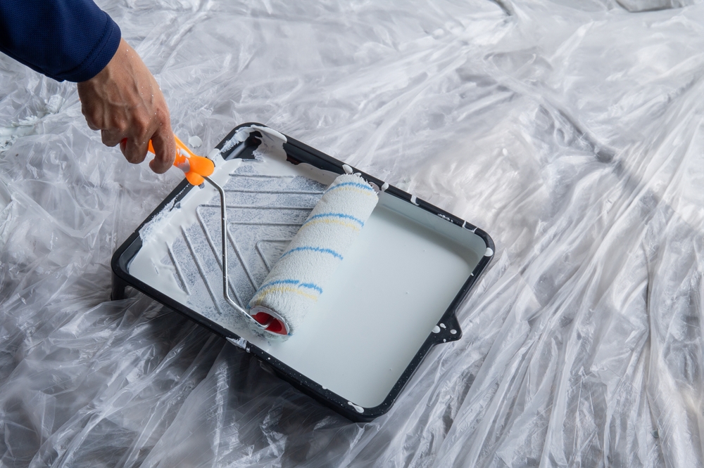 close-up of a painter's hands putting paint on a roller brush